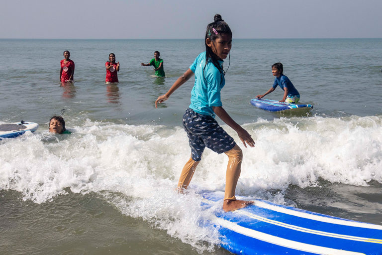 A young person is standing on a surfboard.