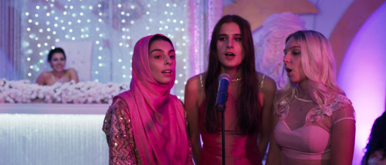 Drei Frauen stehen auf einer Bühne und singen in ein Mikrofon. Eine trägt einen Hijab, die anderen beiden haben offene, lange schwarze beziehungsweise blonde Haare