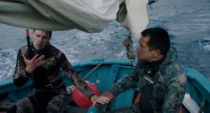 Zwei Männer sitzen in einem Boot in Tauchausrüstung und unterhalten sich.