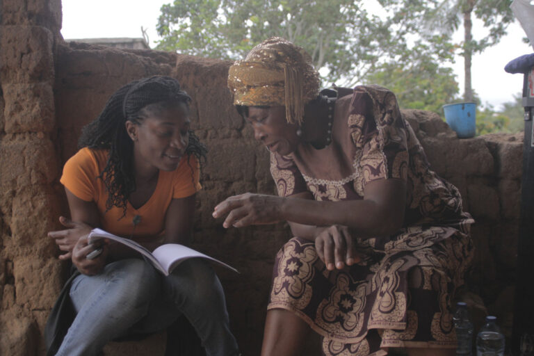 You can see two women who appear to be talking and looking at some papers together.